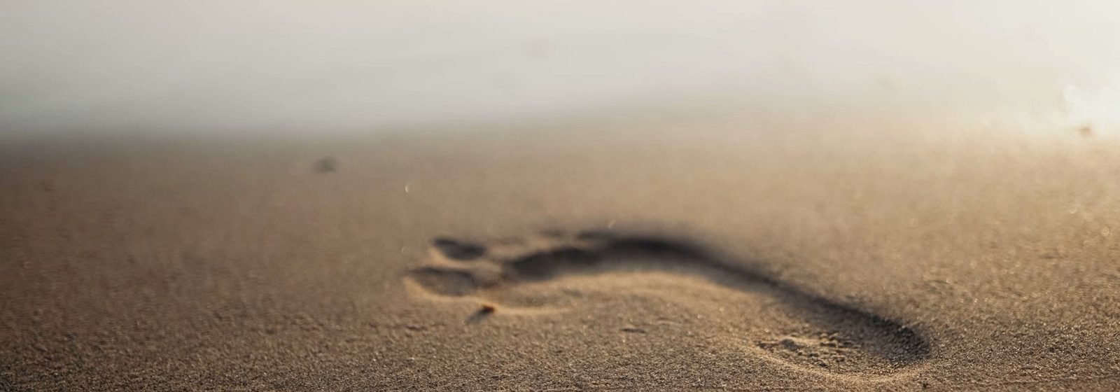 Zu sehen ist ein Fußabdruck im Sand / Jetzt