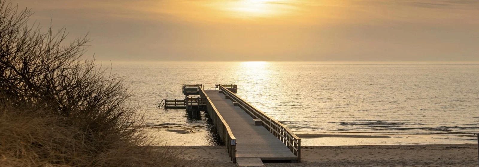 Zu sehen ist eine kleine Seebrücke bei Sonnenaufgang /VAdvent / Weihnachten